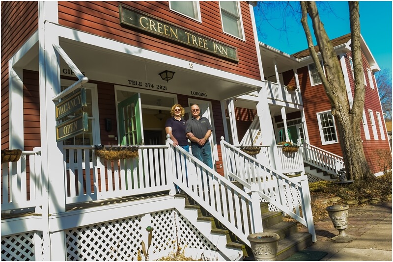 Gary and Connie on stairs with white railing leading up to red building with Green Tree Inn sign.