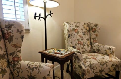 two wingback upholstered armchairs on either side of a window with side table between