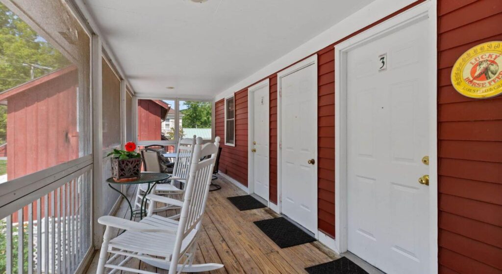 White rocking chairs on long wooden porch in front of rooms