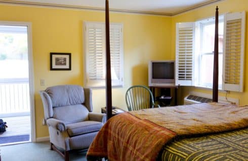 Bedroom painted yellow with dark wooden four-post bed