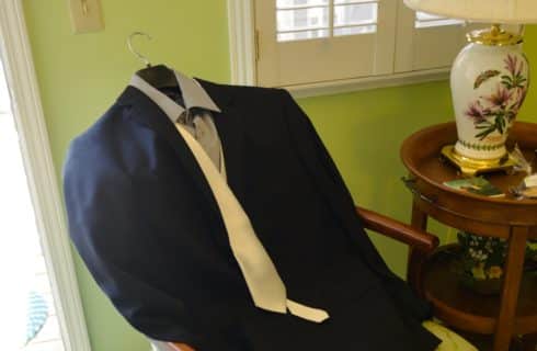 Dark suit with white tie drapped over chair