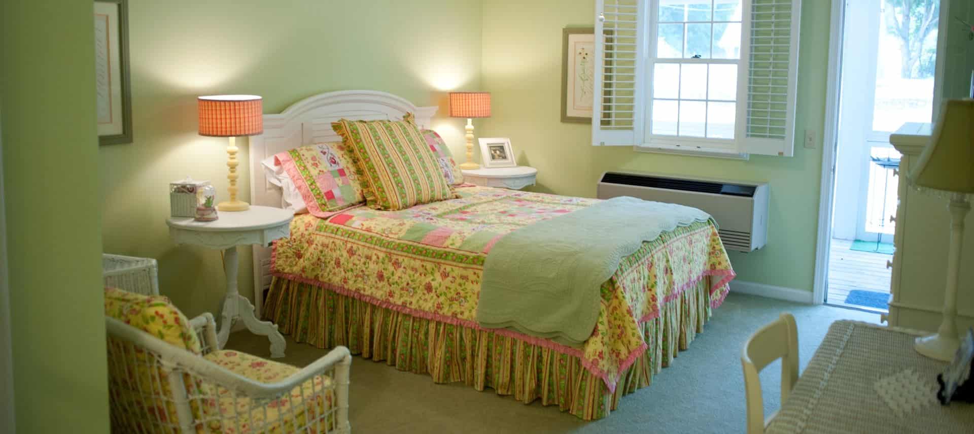 White headboard with sage blanket and green, yellow, and pink comforter next to white side tables