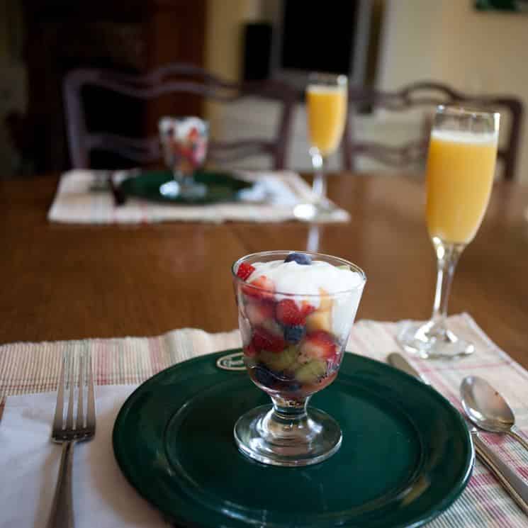 Fruit parfait served in glass dish on top of green plate