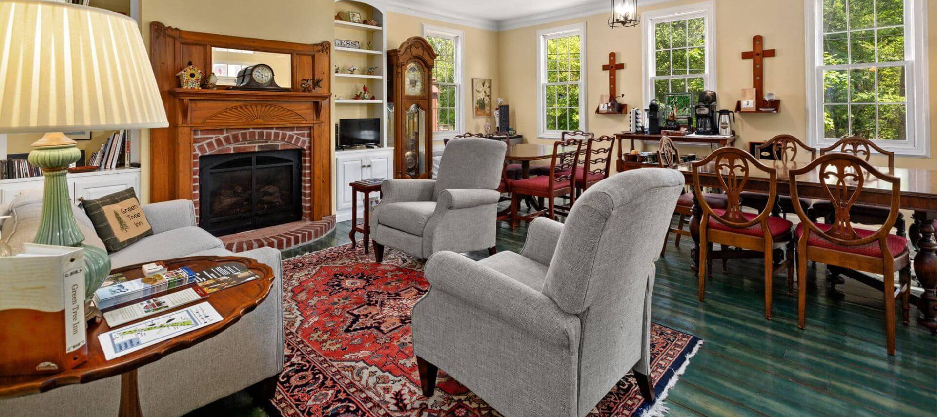 Great room with cream walls, white trim, teal hardwood flooring, multiple dining tables, sitting area, and fireplace
